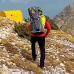 Un operatore del Soccorso Alpino impegnato nelle ricerche cammina lungo i sentieri del Gran Sasso, tra rocce e pendenze impervie. L’intervento si svolge in condizioni difficili, aggravate dal maltempo che ha interessato l’area da ieri sera