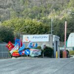 L’ingresso dello stabilimento LFoundry, con le bandiere delle organizzazioni sindacali esposte all’esterno. I sindacati denunciano una disparità di trattamento per i lavoratori in somministrazione esclusi dalle misure di sostegno al reddito.