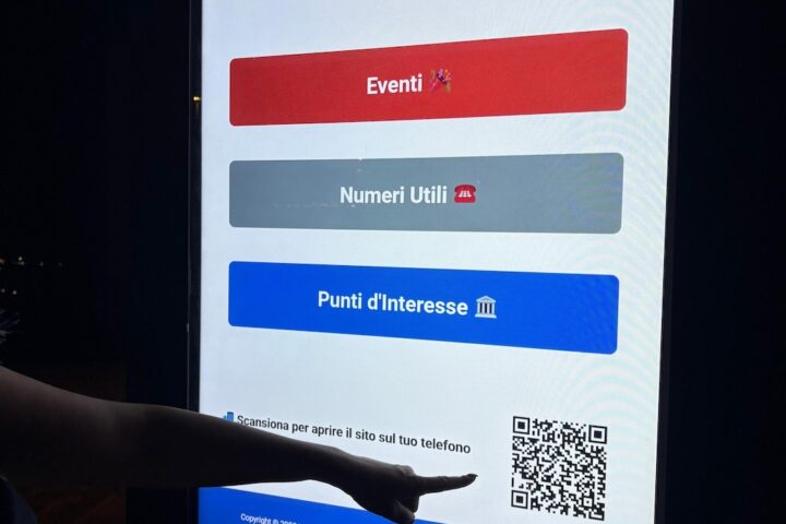 schermi digitali a Montesilvano. una mano indica un qr code