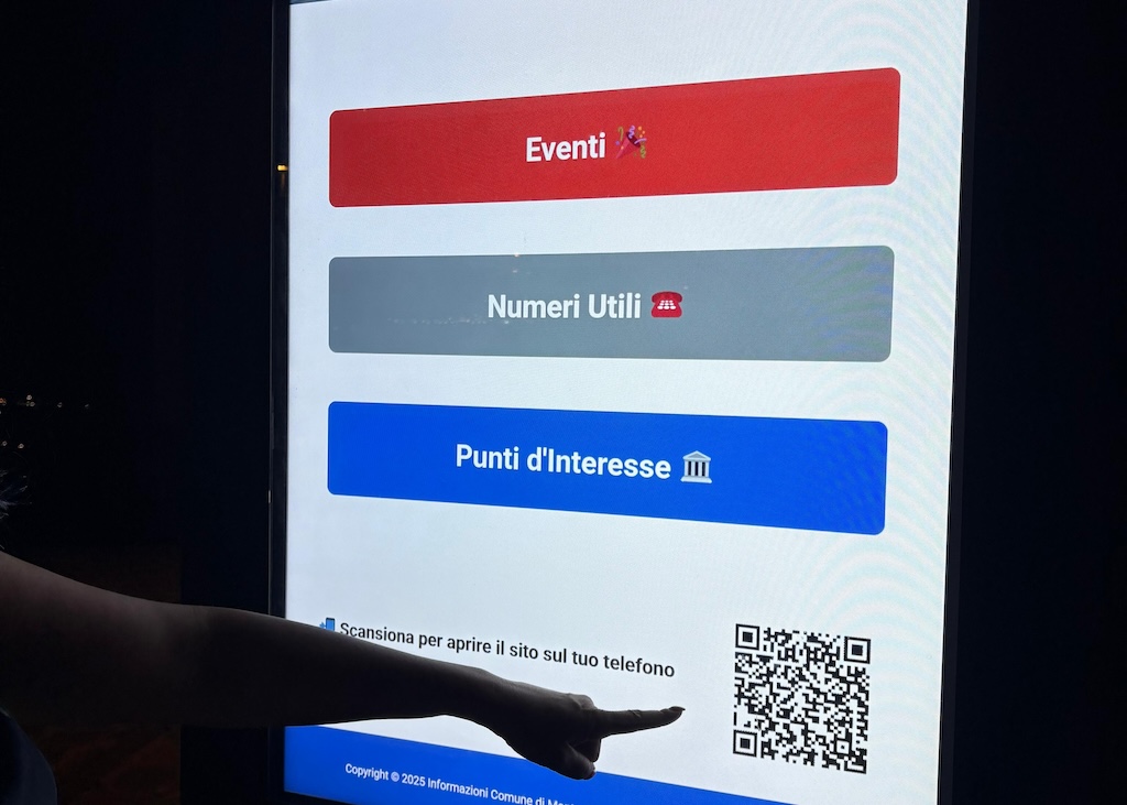 schermi digitali a Montesilvano. una mano indica un qr code