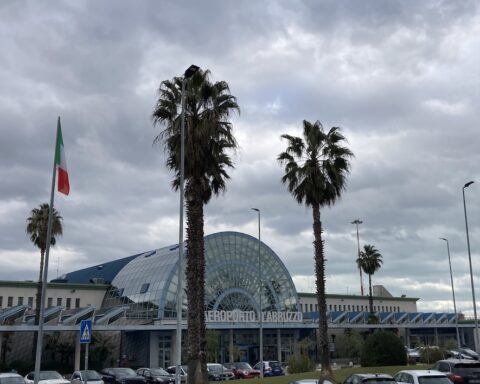 aeroporto d'Abruzzo, nel parcheggio ci sono due palme, le macchine dei passeggeri e d'edificio dell'aeroporto