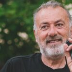 Franco Arminio, poeta e scrittore in primo piano con un microfono in una mano e con un albero sullo sfondo