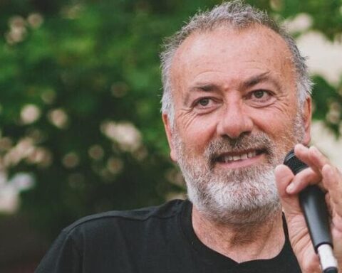Franco Arminio, poeta e scrittore in primo piano con un microfono in una mano e con un albero sullo sfondo