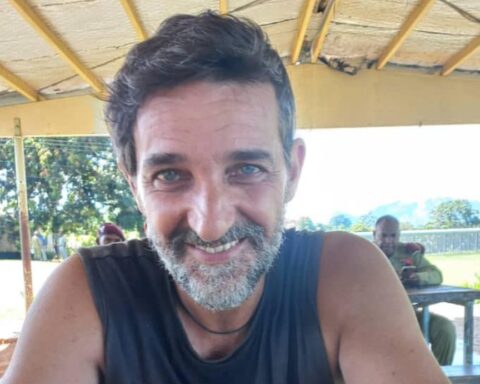 un uomo, carlo d'attanasio, sorride all'aria aperta. si trova sotto un capanno e si intravedono dei soldati stranieri