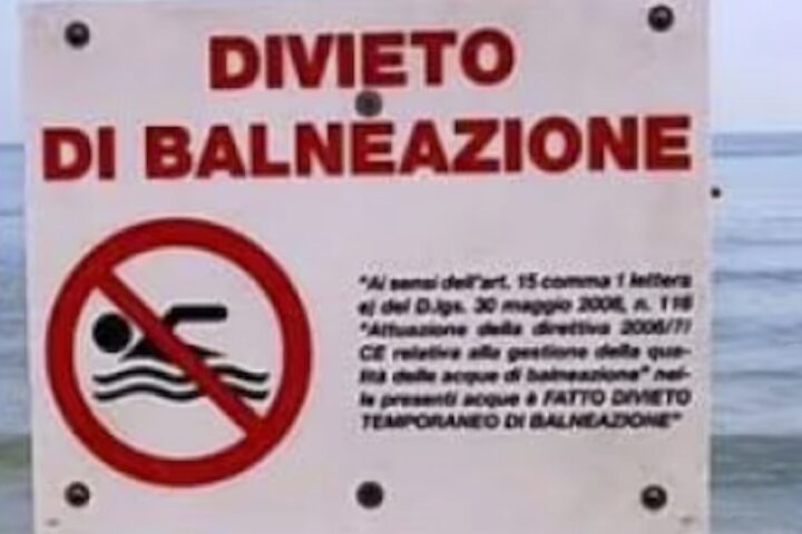 Cartello di divieto di balneazione con sfondo del mare