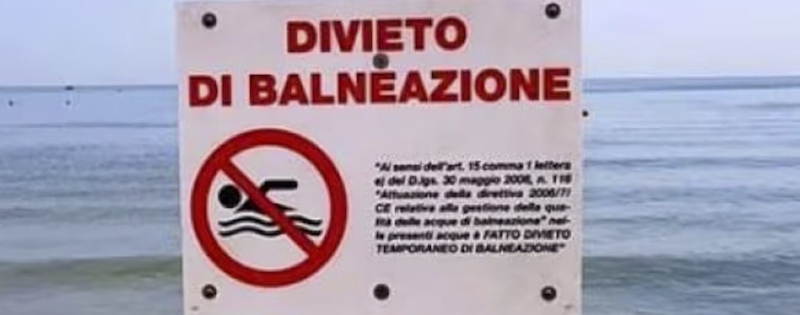 Cartello di divieto di balneazione con sfondo del mare
