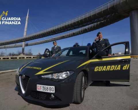 Guardia di Finanza, due finanzieri e un'auto di ordinanza. Sullo sfondo il ponte del mare