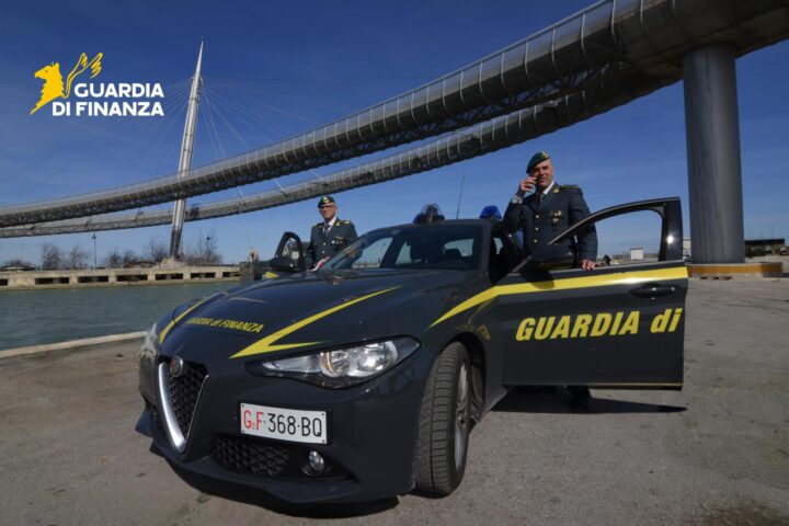 Guardia di Finanza, due finanzieri e un'auto di ordinanza. Sullo sfondo il ponte del mare