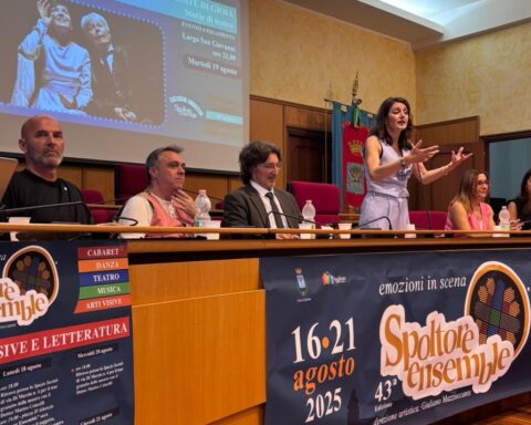alcune persone sedute ad un tavolo parlano e presentano un evento