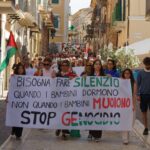 persone sfilano in una marcia per la pace con striscioni e bandiere