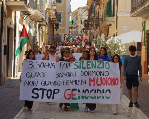 persone sfilano in una marcia per la pace con striscioni e bandiere