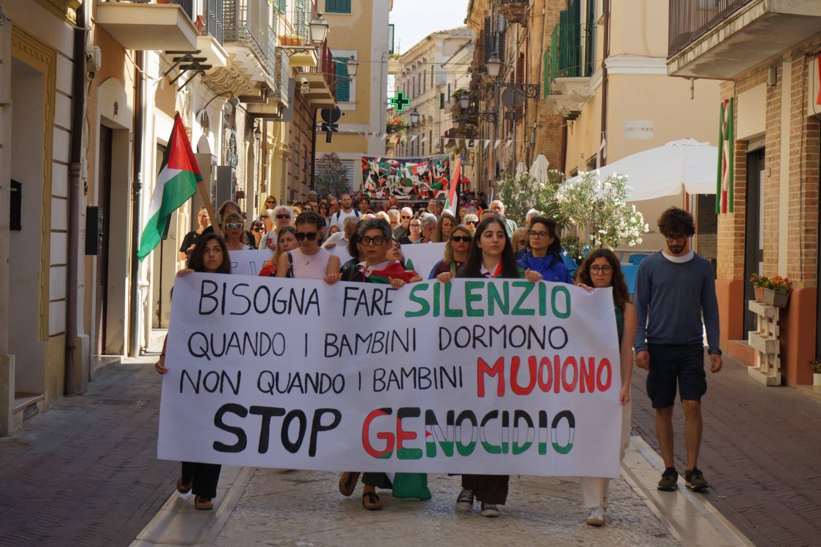 persone sfilano in una marcia per la pace con striscioni e bandiere
