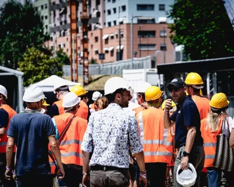 Operai e tecnici in cantiere con caschetti e giubbotti arancioni, simbolo del mondo del lavoro in Abruzzo. L’immagine richiama il tema della precarietà e della crisi occupazionale al centro dello scontro politico.