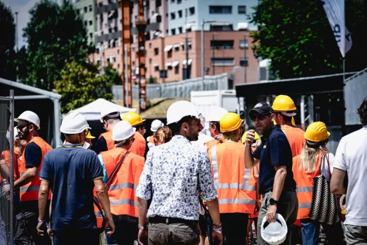 Operai e tecnici in cantiere con caschetti e giubbotti arancioni, simbolo del mondo del lavoro in Abruzzo. L’immagine richiama il tema della precarietà e della crisi occupazionale al centro dello scontro politico.