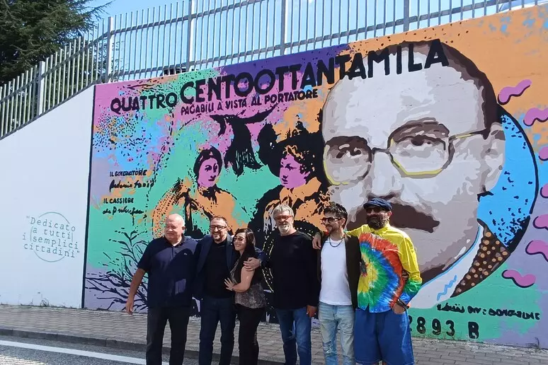 Il murales dedicato a Mario Magnotta inaugurato a Colle Sapone, firmato dall’artista Daniele Gottastia. Accanto all’opera, la figlia Romina, il sindaco Biondi e gli autori degli scherzi riuniti per celebrare il “Magnotta Day”