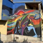 Uno dei nuovi murales realizzati a Sante Marie sulle case di edilizia residenziale pubblica: colori vivaci e figure simboliche trasformano le facciate in opere d’arte