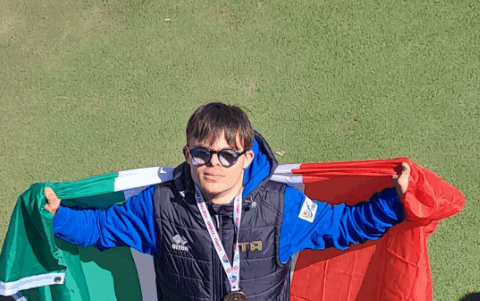 L’atleta abruzzese Nando D’Agostino festeggia la medaglia d’oro ai Mondiali FISDIR di atletica leggera a Brisbane, sventolando la bandiera italiana sul podio. Il giovane marciatore della Polisportiva Tethys di Chieti ha conquistato il titolo iridato nei 1500 metri.