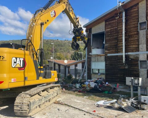 Escavatore in azione nel villaggio Map di San Gregorio, dove sono iniziati gli interventi di demolizione di dieci alloggi inutilizzati