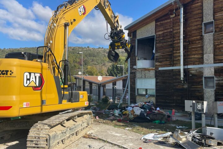 Escavatore in azione nel villaggio Map di San Gregorio, dove sono iniziati gli interventi di demolizione di dieci alloggi inutilizzati