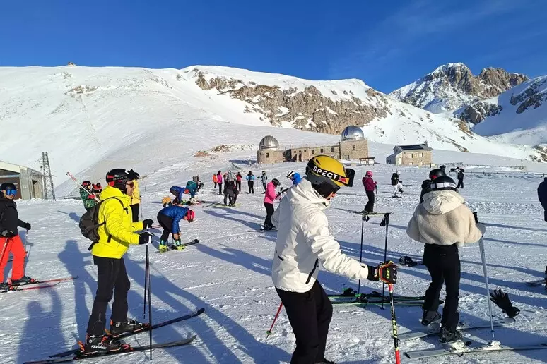 Sciatori e appassionati affollano le piste delle Fontari a Campo Imperatore nel giorno della riapertura della stagione invernale. Sullo sfondo l’altopiano innevato e le strutture dell’osservatorio, in una giornata di sole e grande affluenza