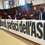 Protesta delle opposizioni durante il Consiglio comunale dell’Aquila, con l’esposizione di uno striscione sulla crisi finanziaria di ASM.