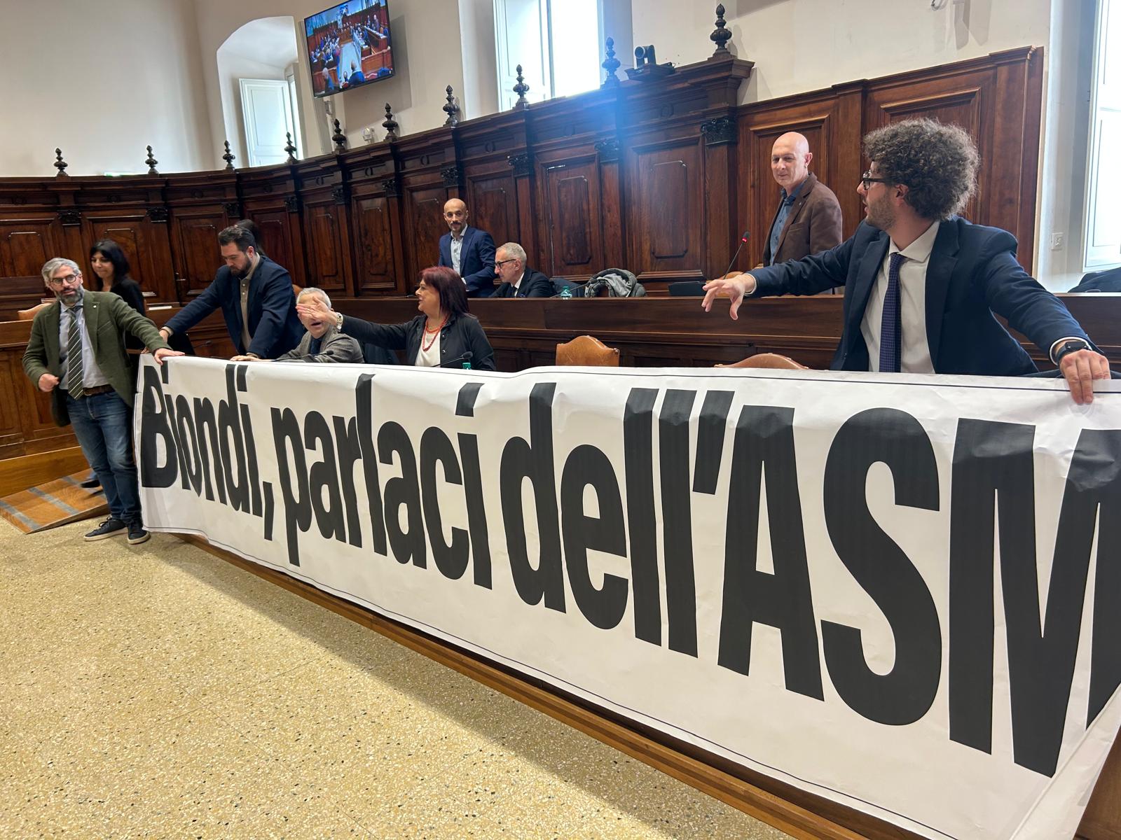 Protesta delle opposizioni durante il Consiglio comunale dell’Aquila, con l’esposizione di uno striscione sulla crisi finanziaria di ASM.